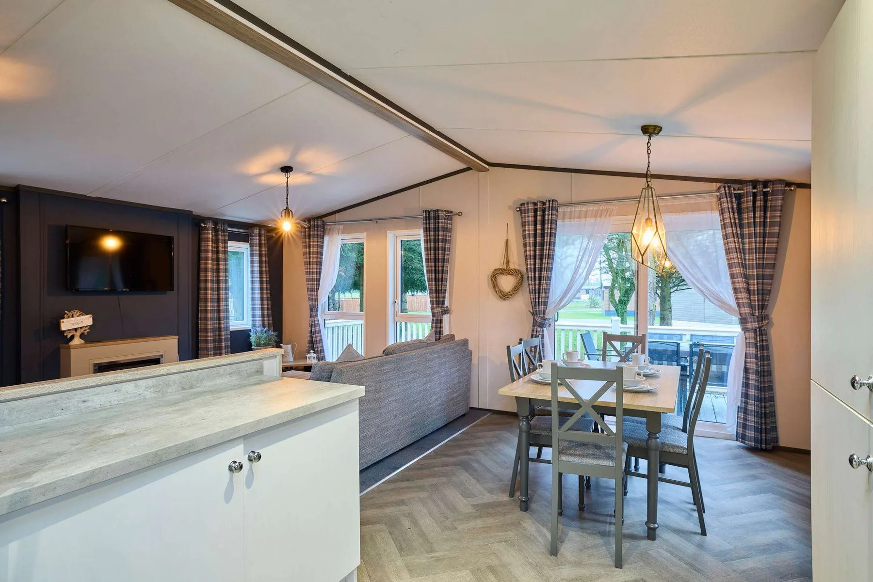 Una sala y comedor abiertos tienen asientos, una mesa y grandes ventanas.