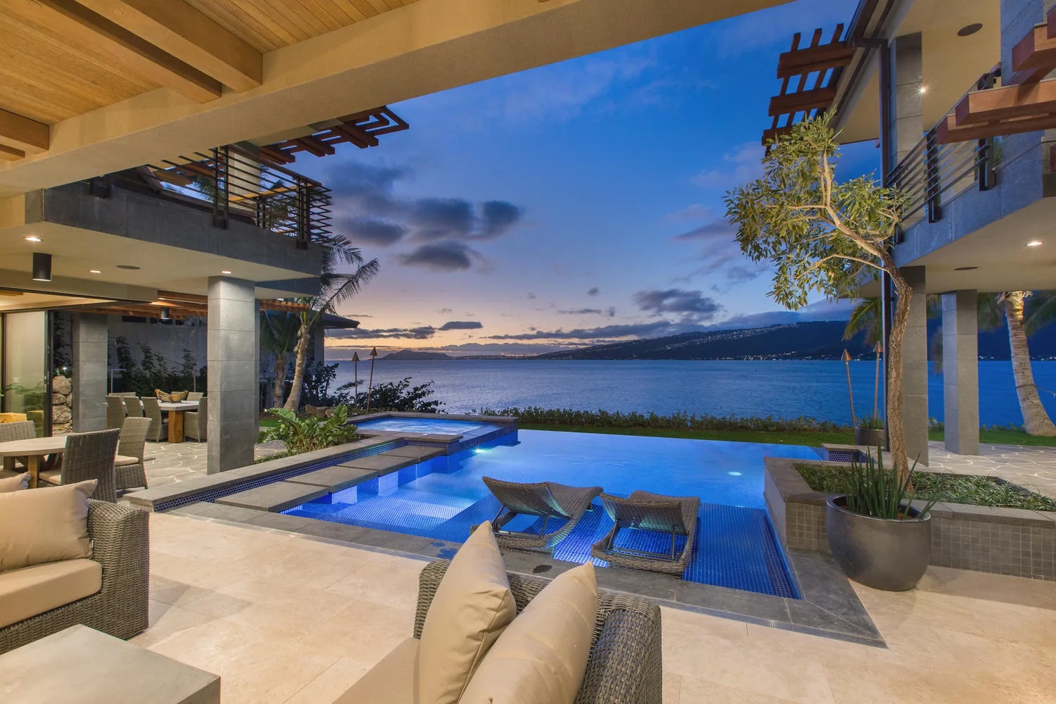 Outdoor pool and seating overlook a lake at sunset.