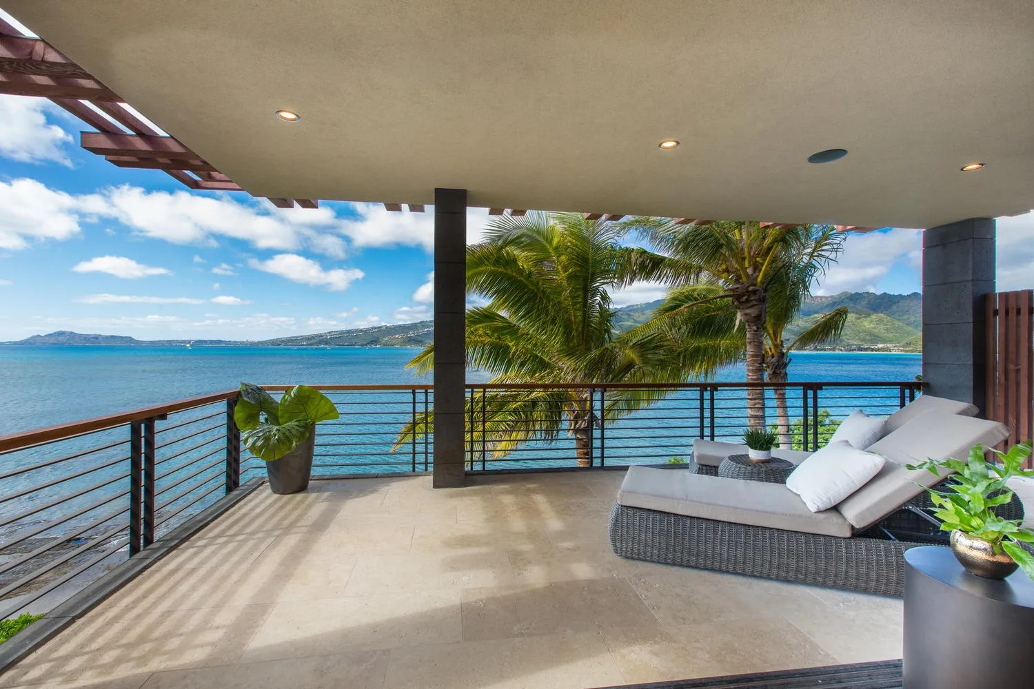 Covered outdoor terrace with lounge seating overlooking the ocean.