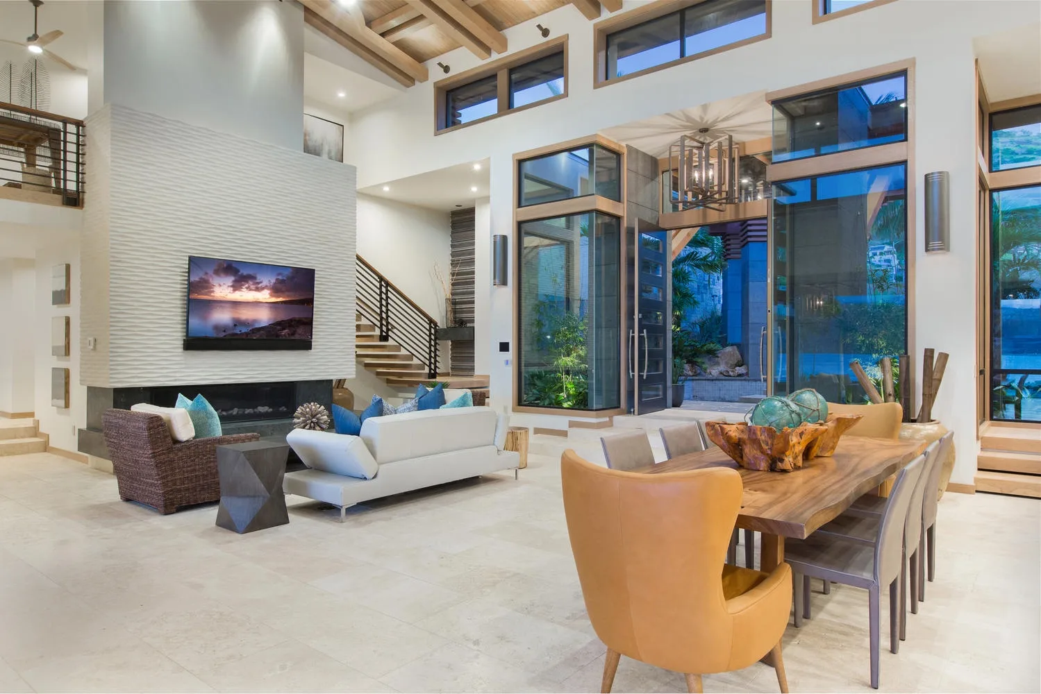 A spacious living room with seating, a television, and tall windows.