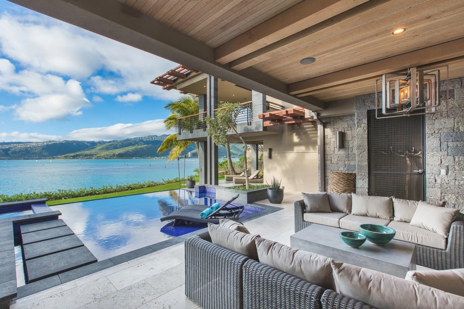 A covered outdoor seating area overlooks a pool and a lake.