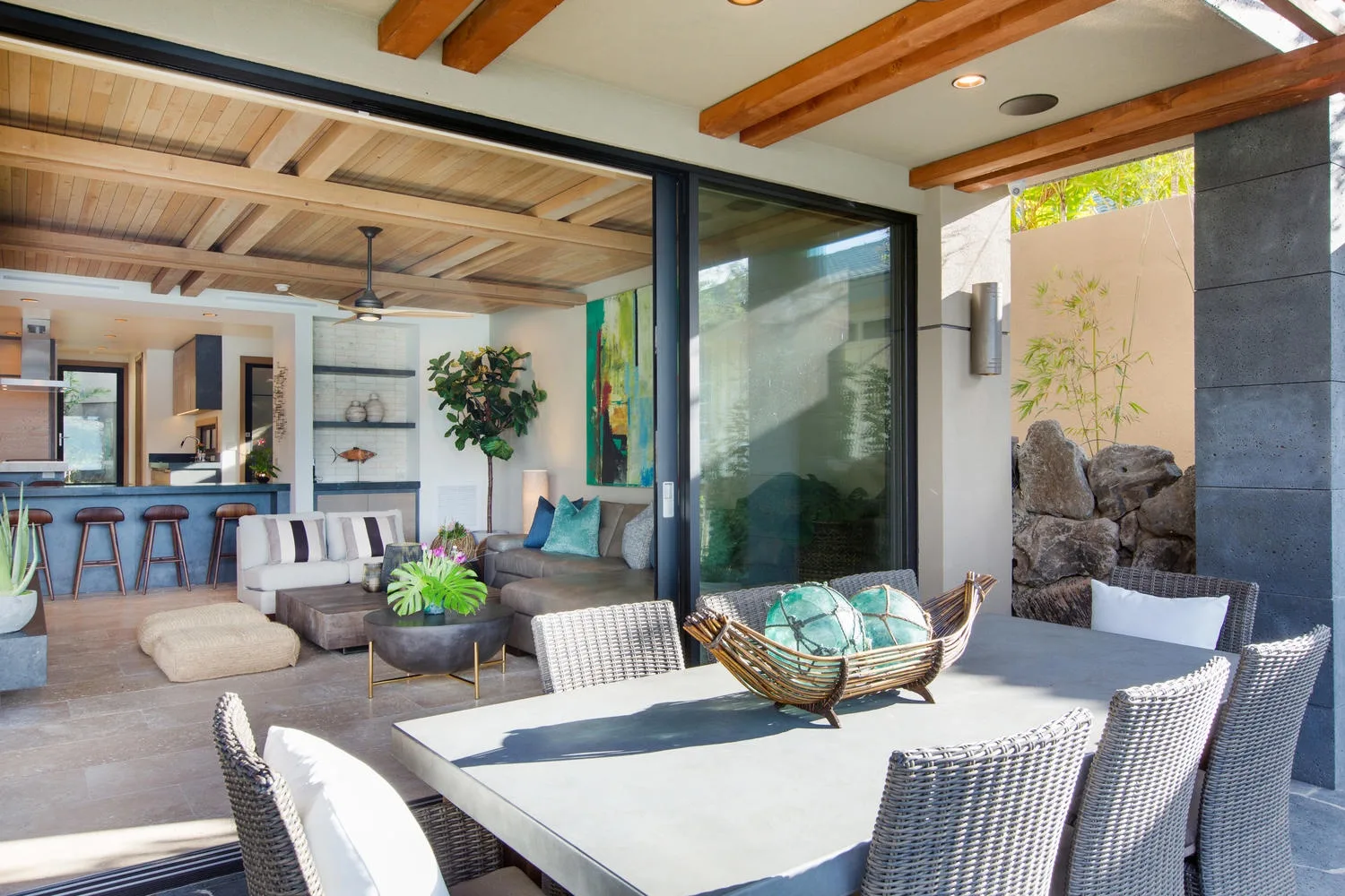 An outdoor dining area beside a covered lounge with sliding glass doors.
