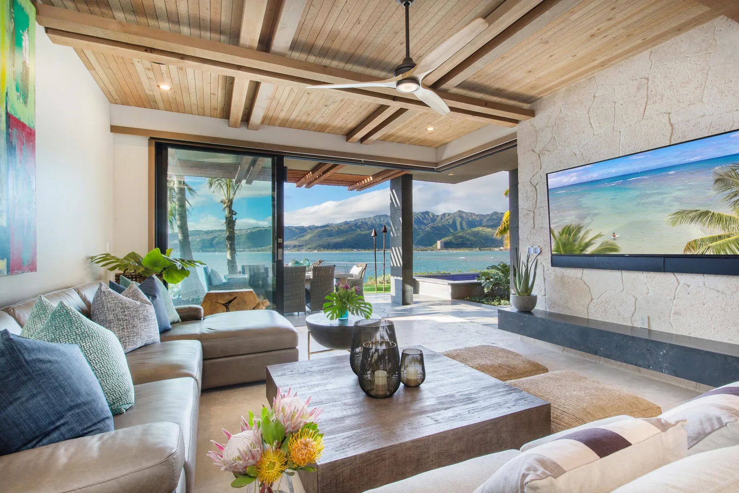 A living room with seating, a coffee table, and wide windows overlooking the water.