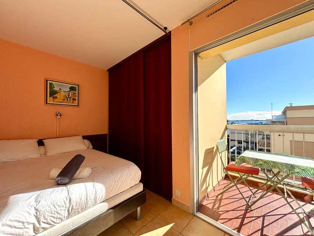 Un dormitorio se abre a un balcón con asientos al aire libre y vistas al mar.