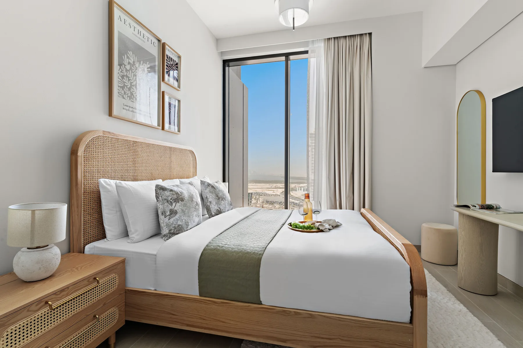 A bright bedroom with a neatly made bed beside a large window.