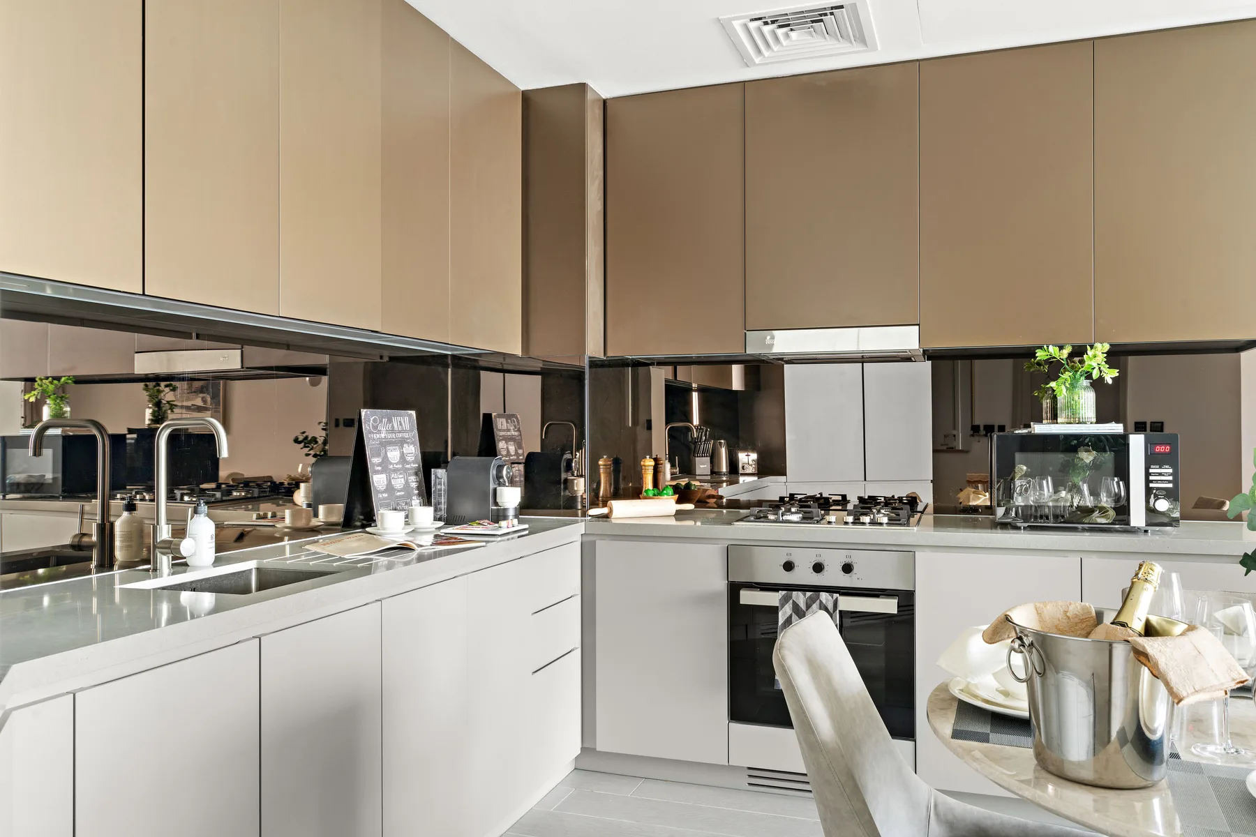 A modern kitchen with light cabinets, a central oven, and a dining table.