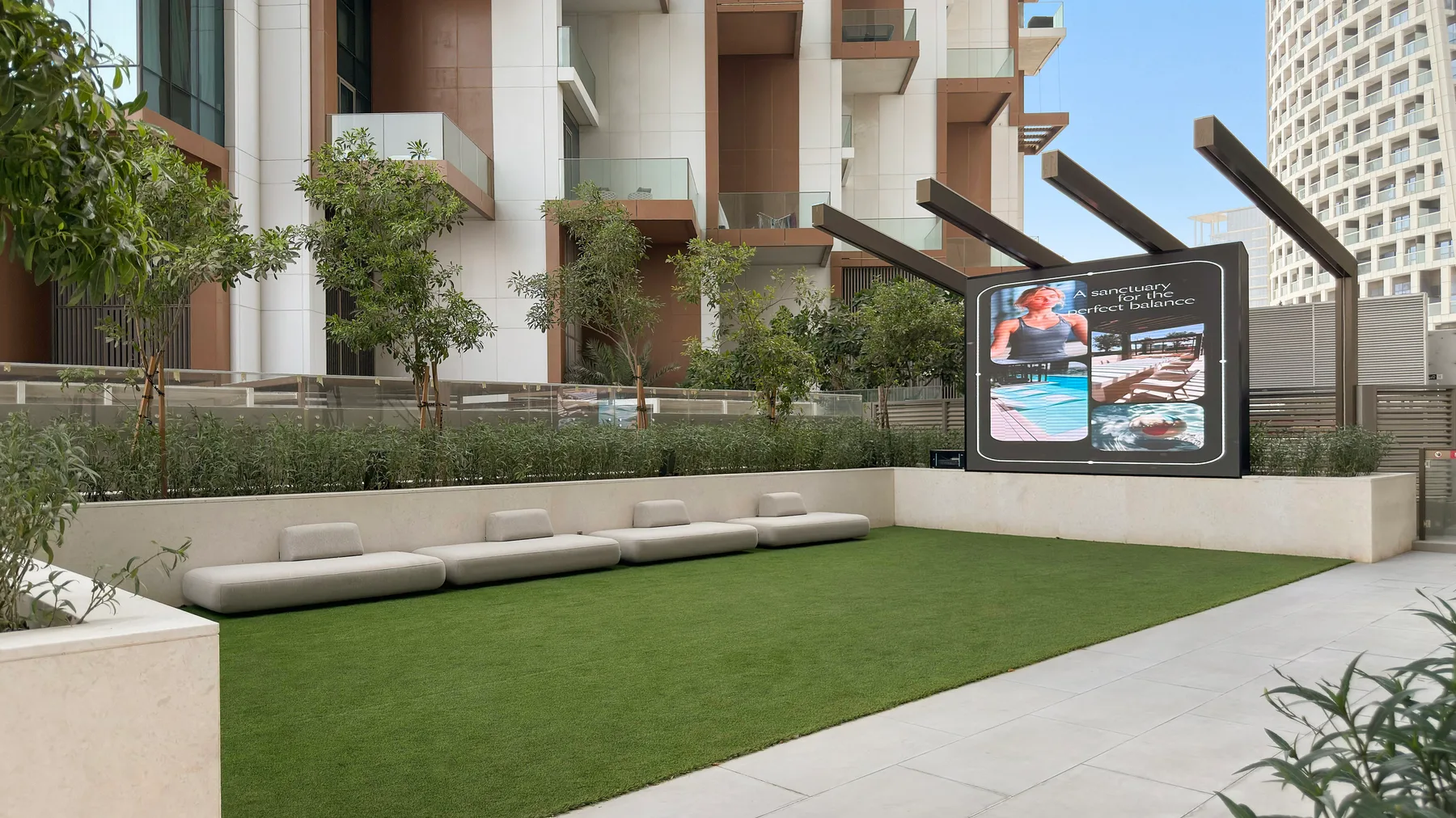 An outdoor landscaped courtyard features a broad green lawn and built-in seating.