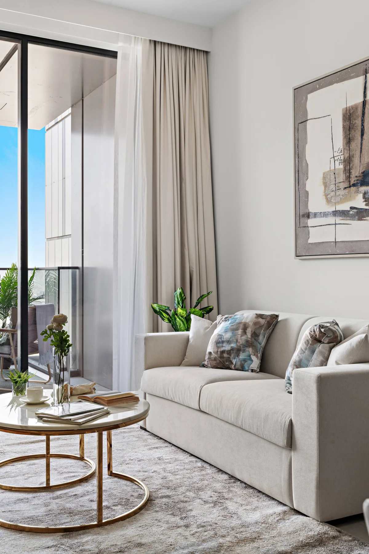 A bright living room with a light-colored sofa beside tall glass doors.