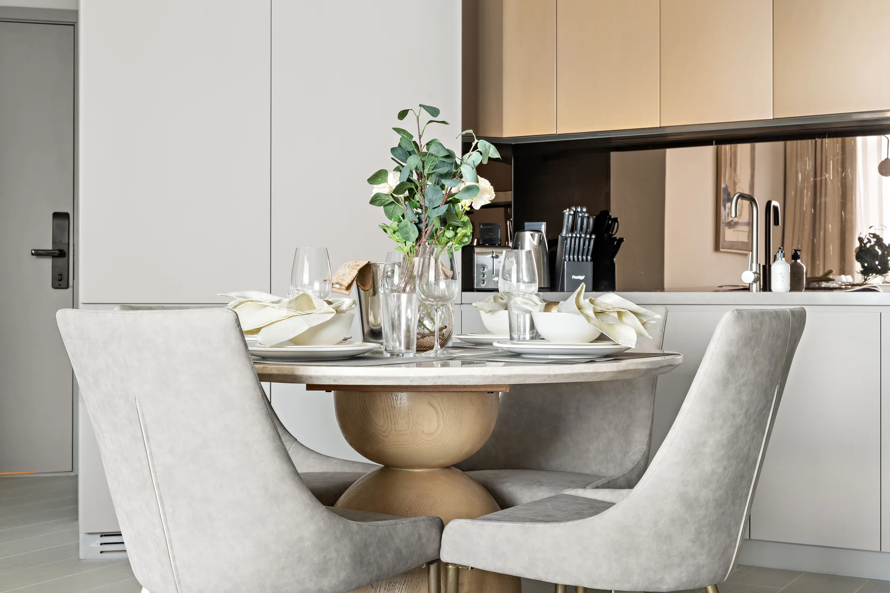 A dining area features a round table set with dishes and chairs.