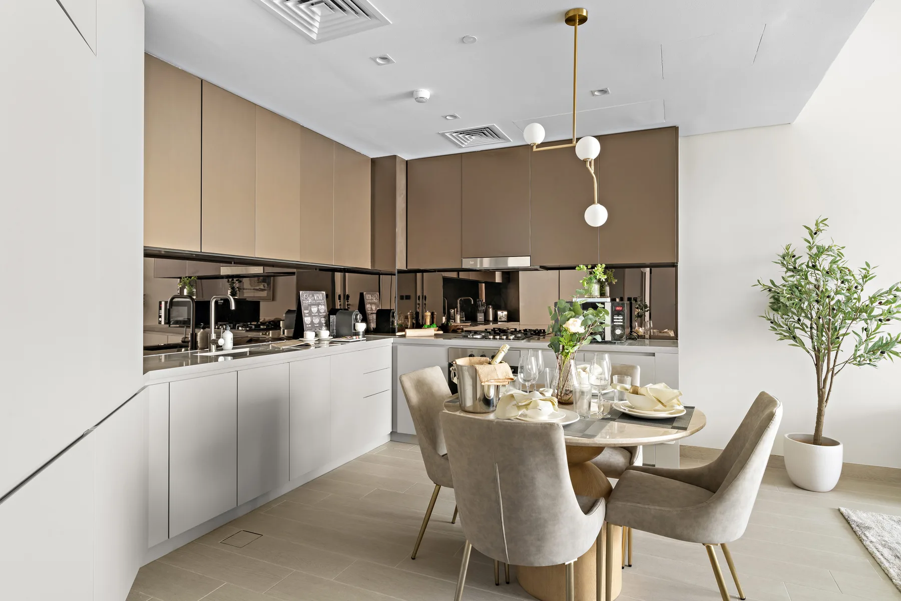 A modern kitchen and dining area with a set table and upholstered seating.