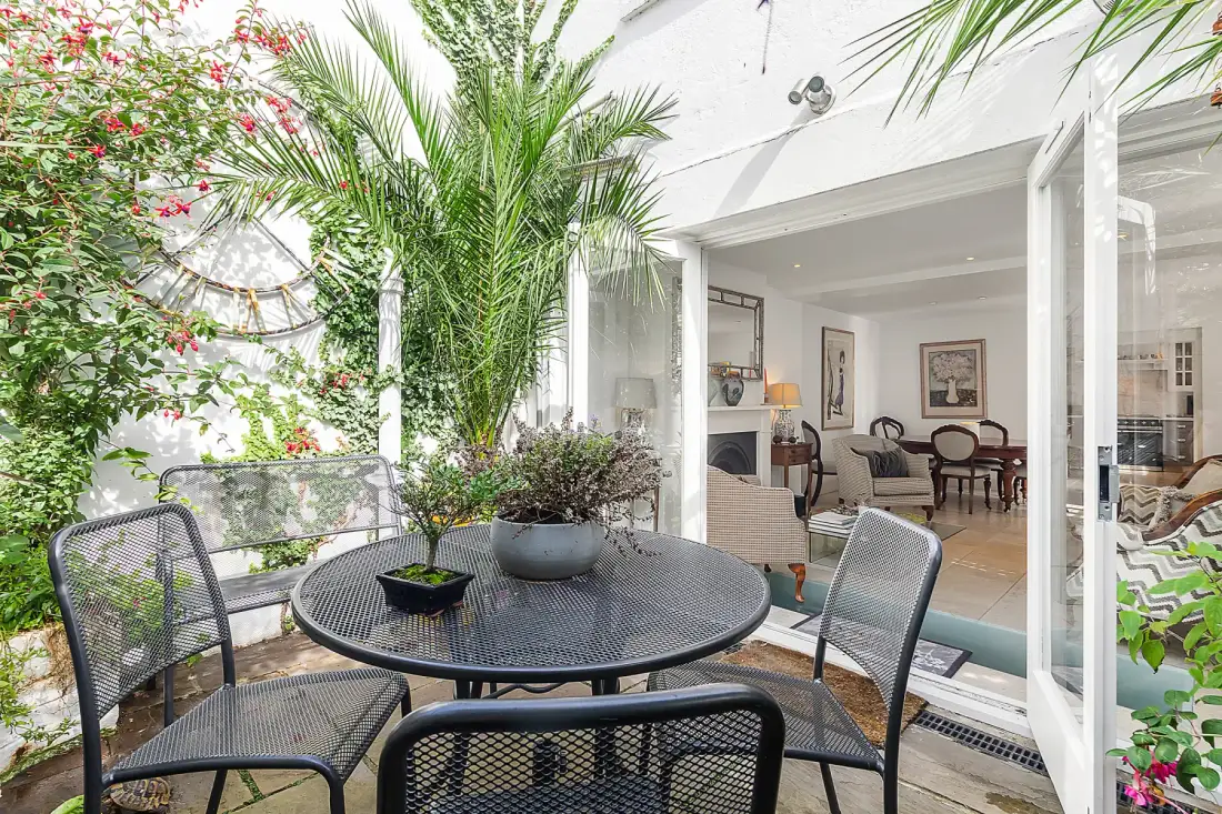 Un patio con una mesa redonda y asientos junto a una sala abierta.