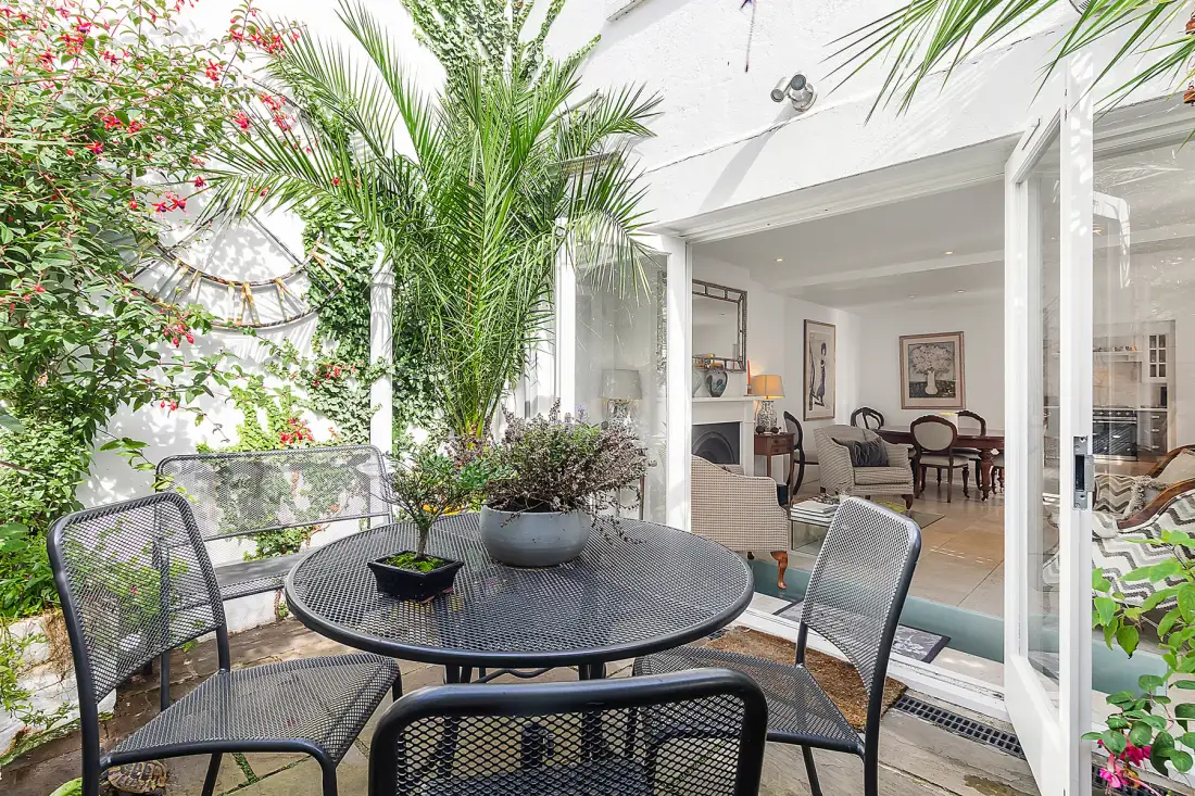 A patio seating area with a round table opens onto a bright indoor dining space.