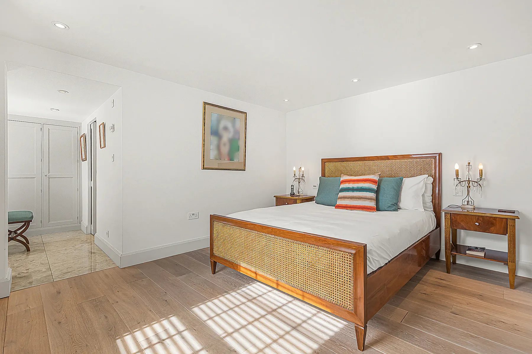 Un dormitorio luminoso con una cama, mesitas de noche y una puerta.