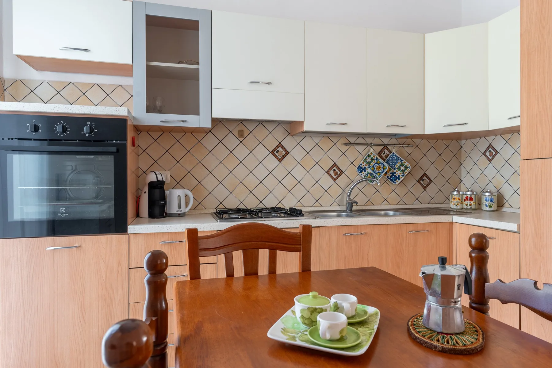 Una cocina con gabinetes de madera, un salpicadero de azulejos y una mesa de comedor.