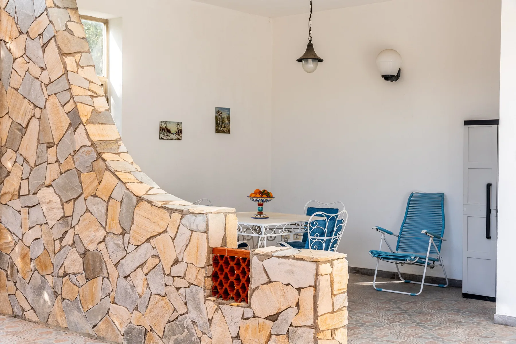 Una luminosa zona interior de comedor y descanso con un tabique de piedra y una mesa pequeña.