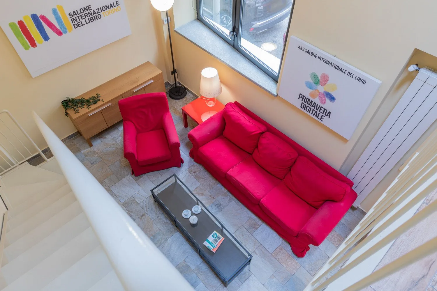 A living room with bright pink seating, a coffee table, and large windows.