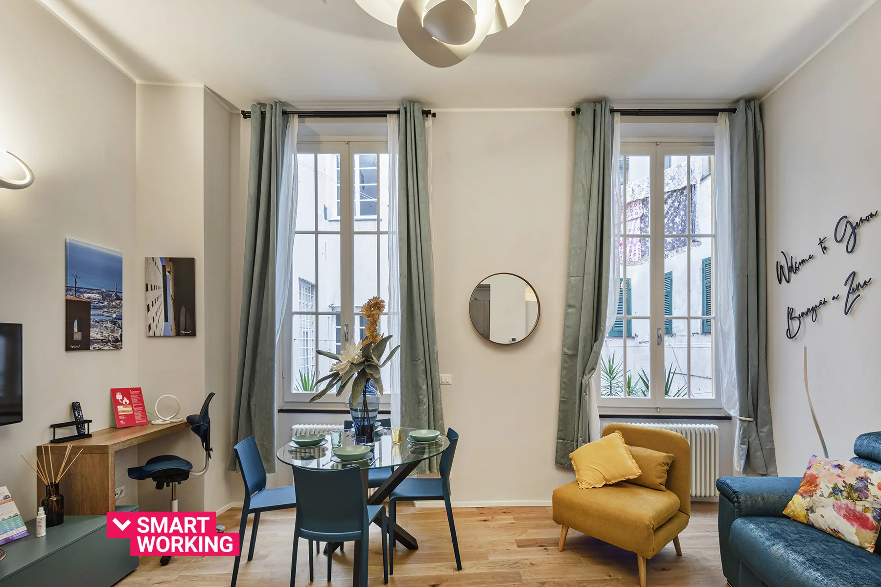 Una sala luminosa con ventanas altas, una mesa pequeña y asientos.