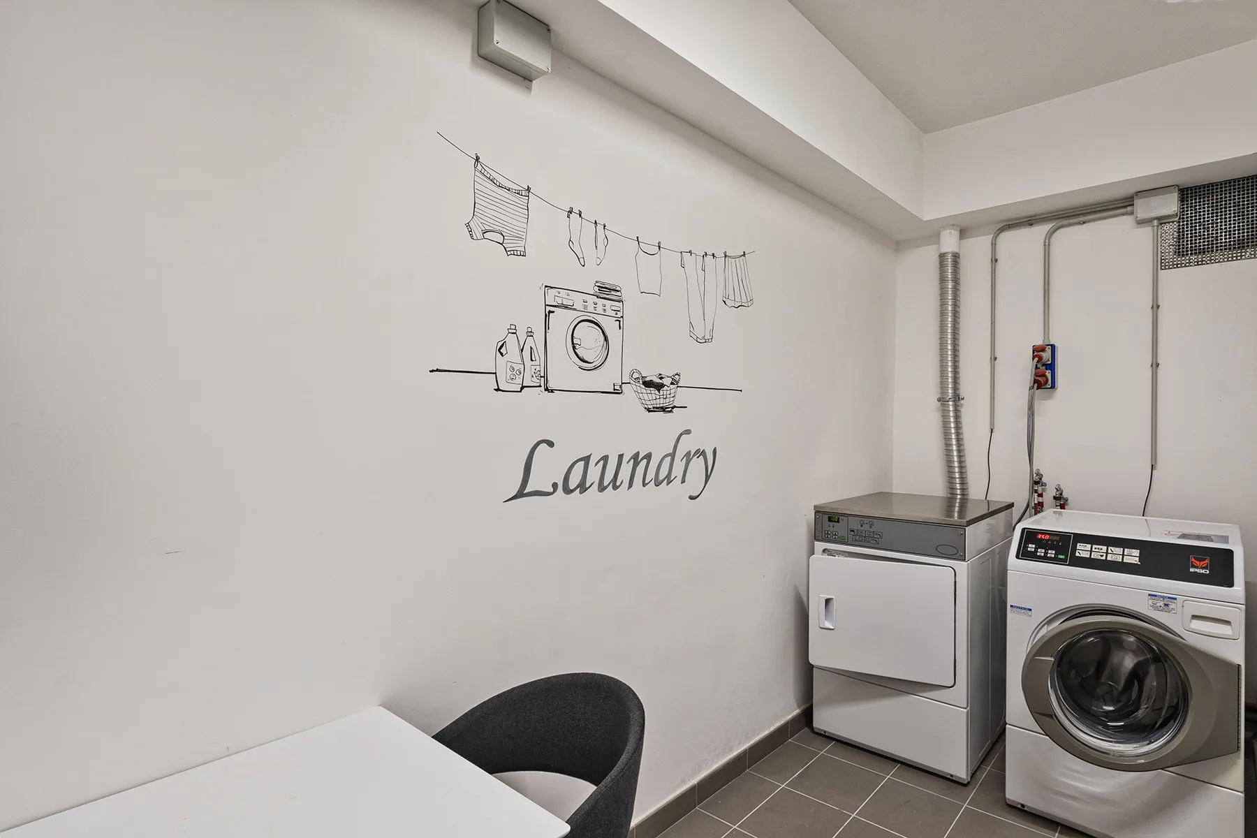Lavandería con una lavadora y una secadora junto a la pared.