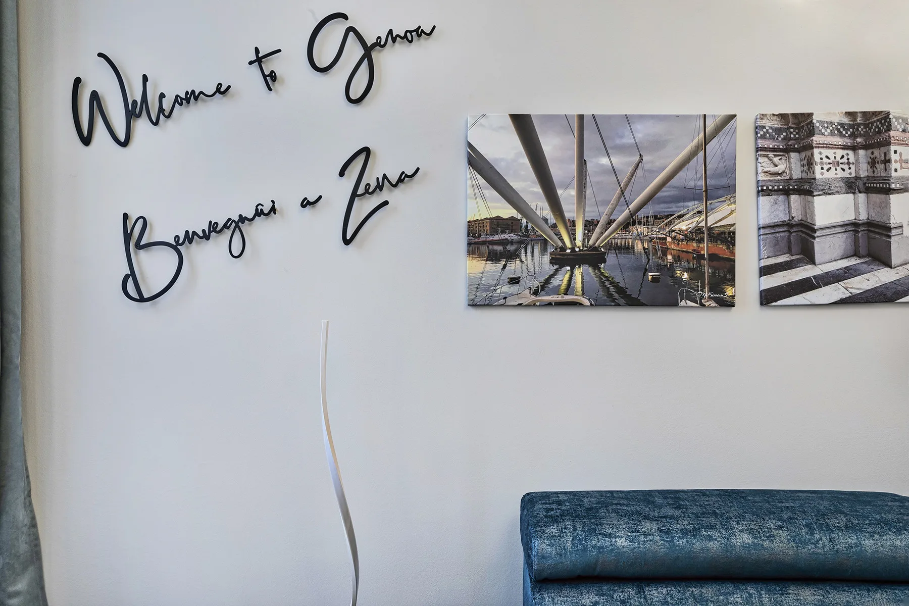 Una pared muestra letras manuscritas y dos fotografías sobre un asiento tapizado azul.