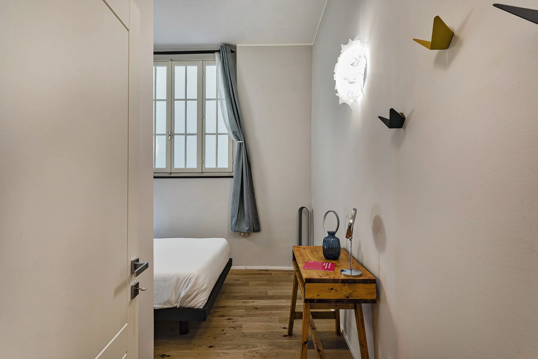 Un dormitorio con una cama junto a una ventana y un pequeño escritorio.