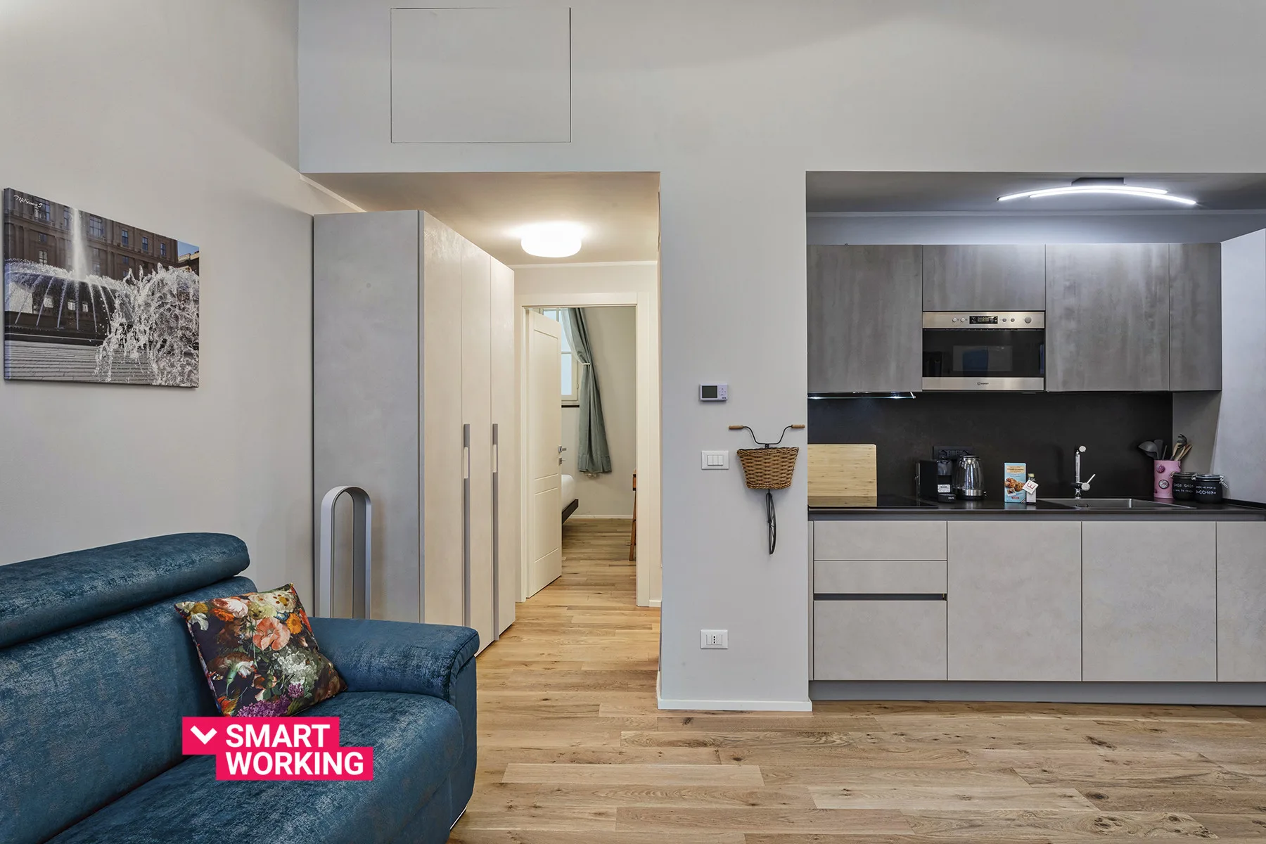 Una sala de estar moderna se abre a una cocina, con asientos azules en primer plano.
