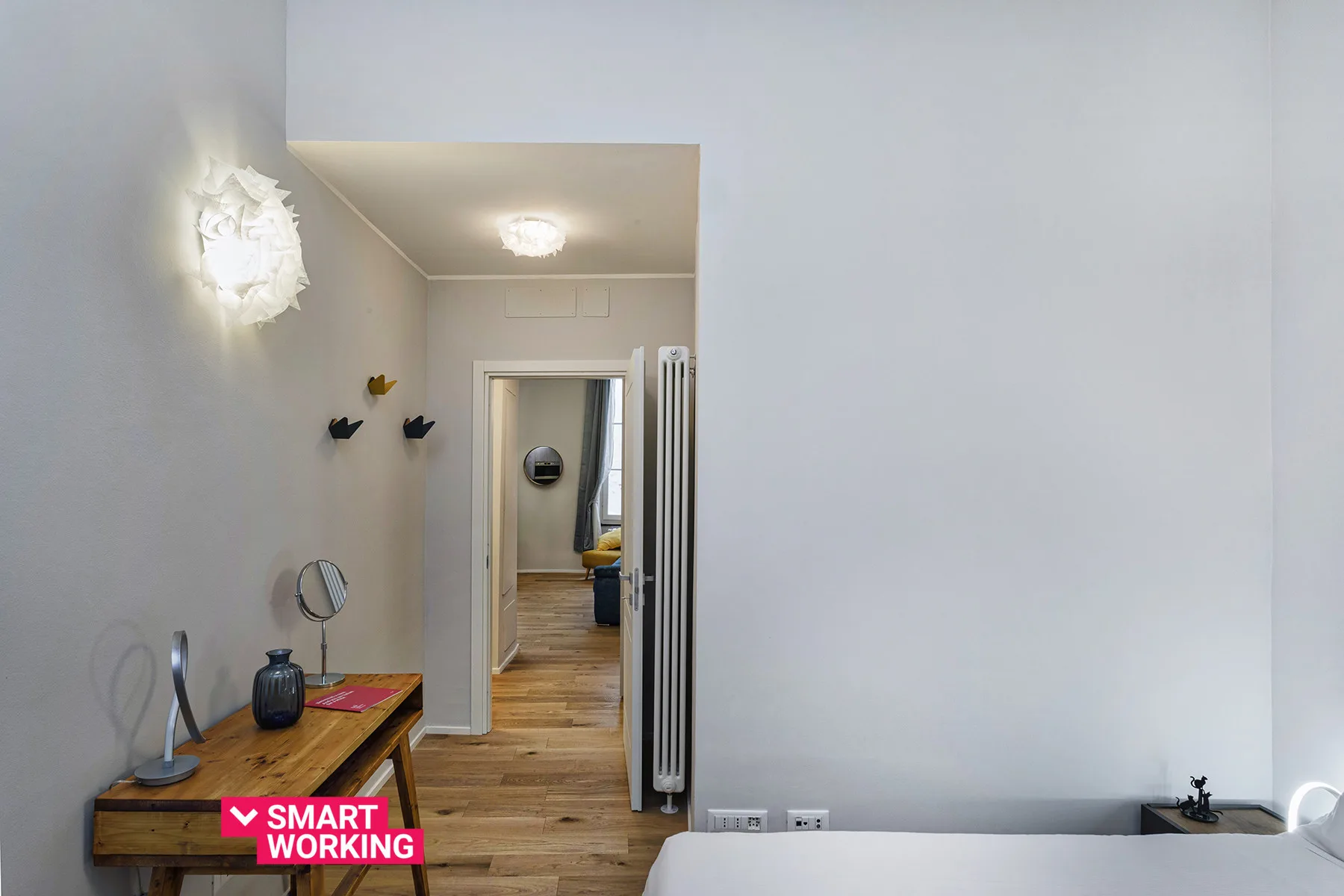 Un pasillo interior luminoso con suelo de madera y una pequeña mesa consola.