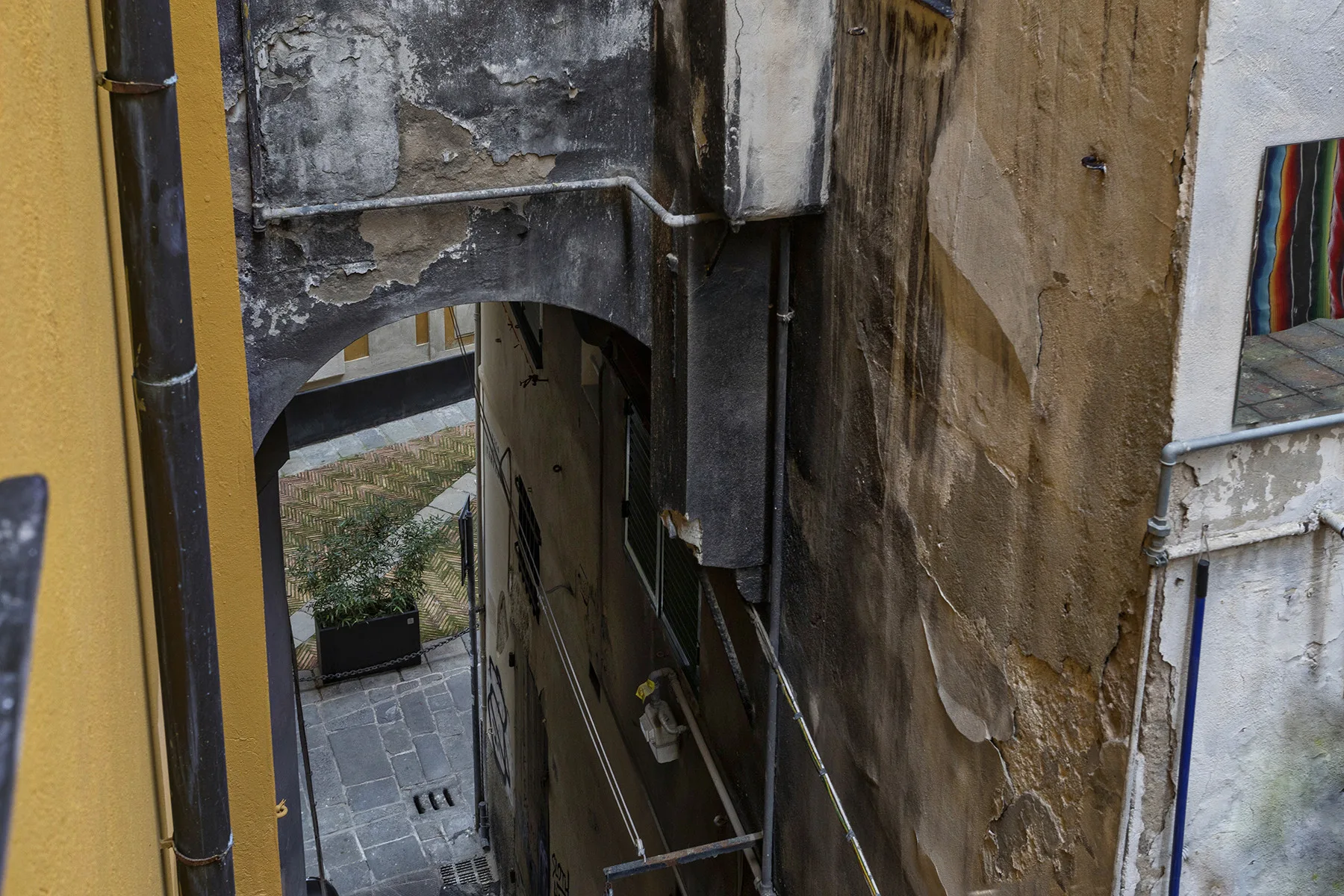 Un pasaje estrecho entre edificios antiguos da a un pequeño patio pavimentado.