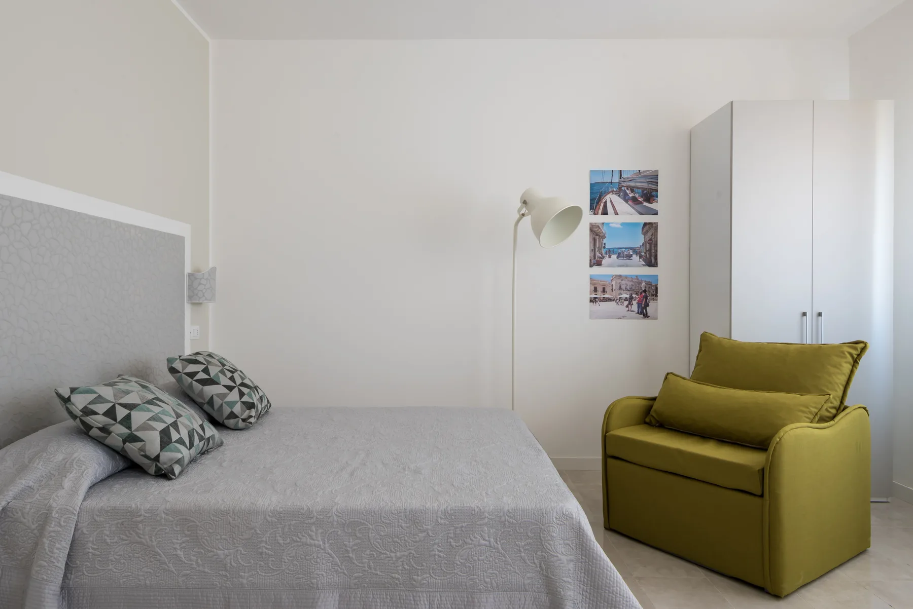 Un dormitorio con una cama y un sillón verde junto a un armario.