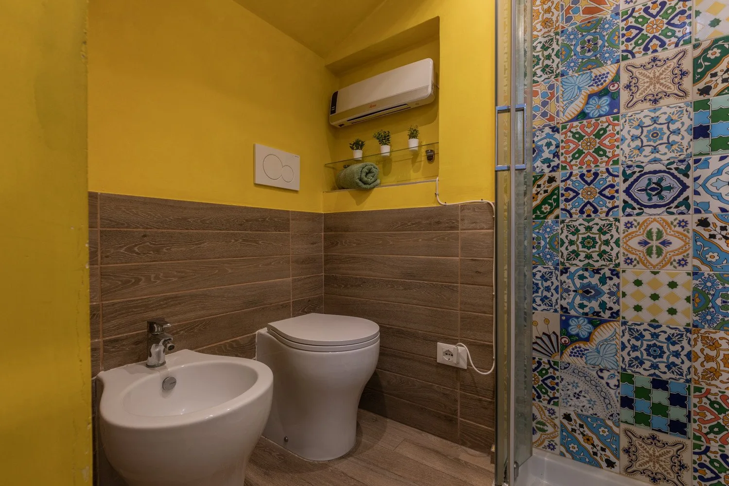 A colorful bathroom with a toilet, sink, and patterned tile wall.