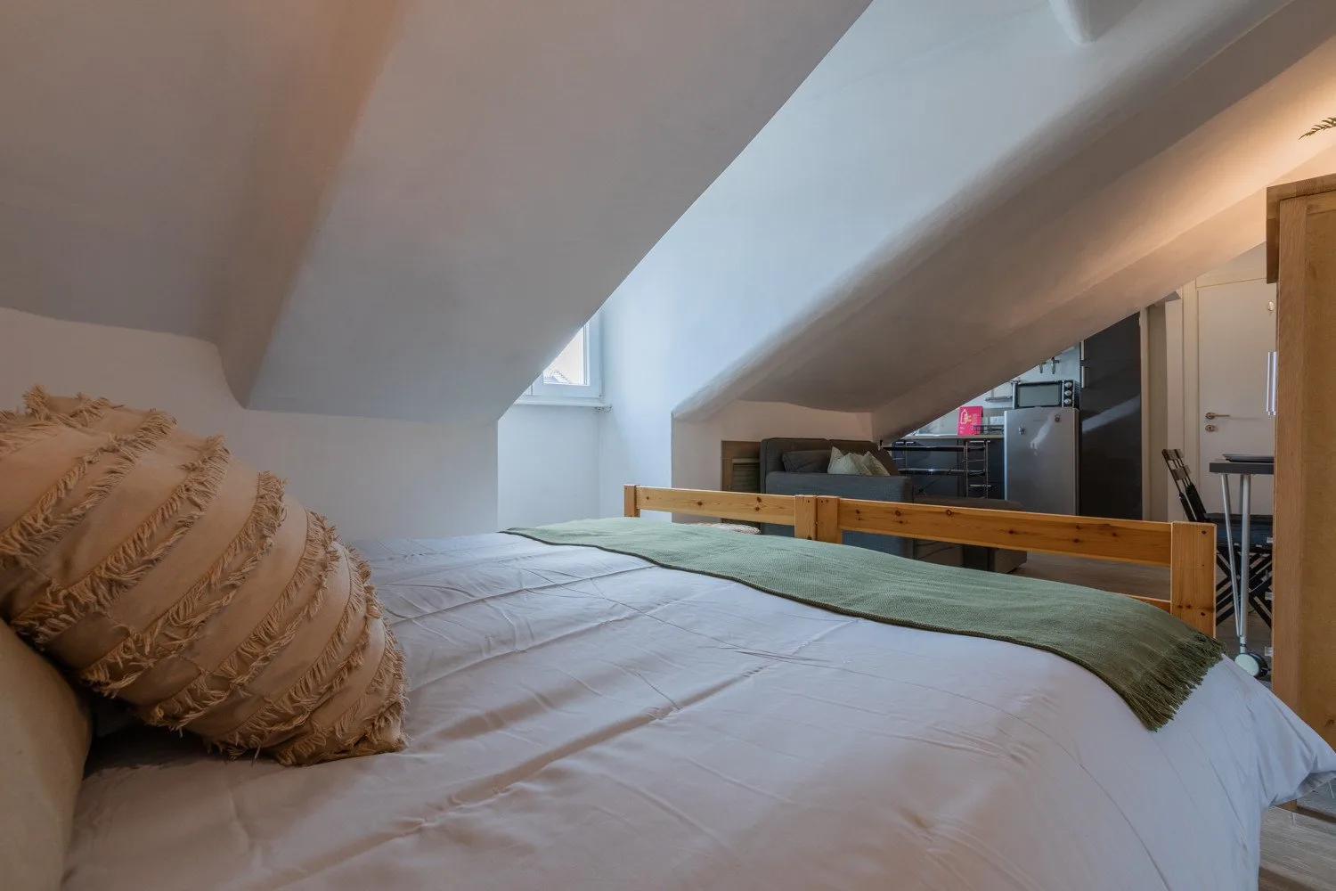 A low-ceiling sleeping area with a bed and a small window.