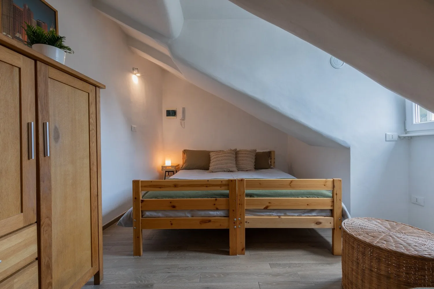 A bedroom with a wooden bed beneath a sloped ceiling.