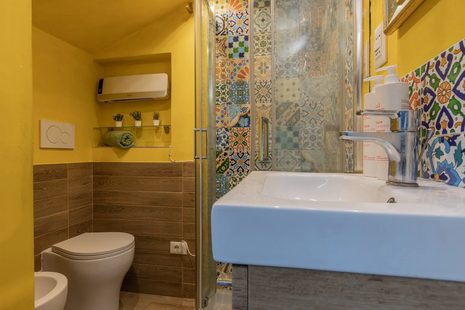 A colorful tiled bathroom with a large sink and glass shower.