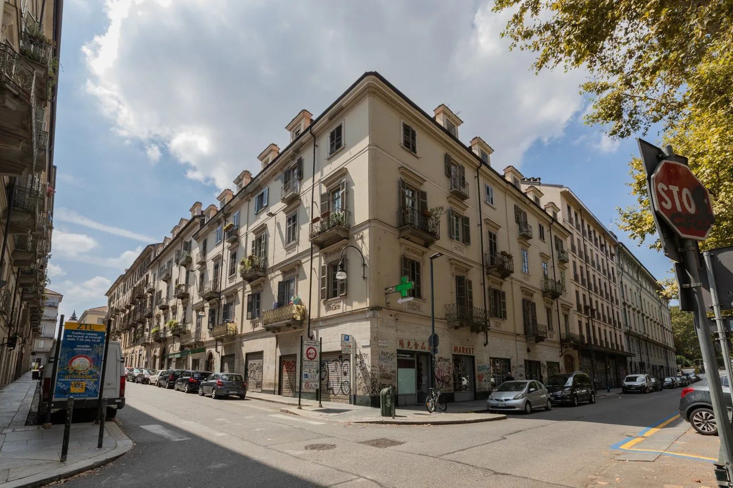 A city street corner lined with multi-story buildings and parked cars.