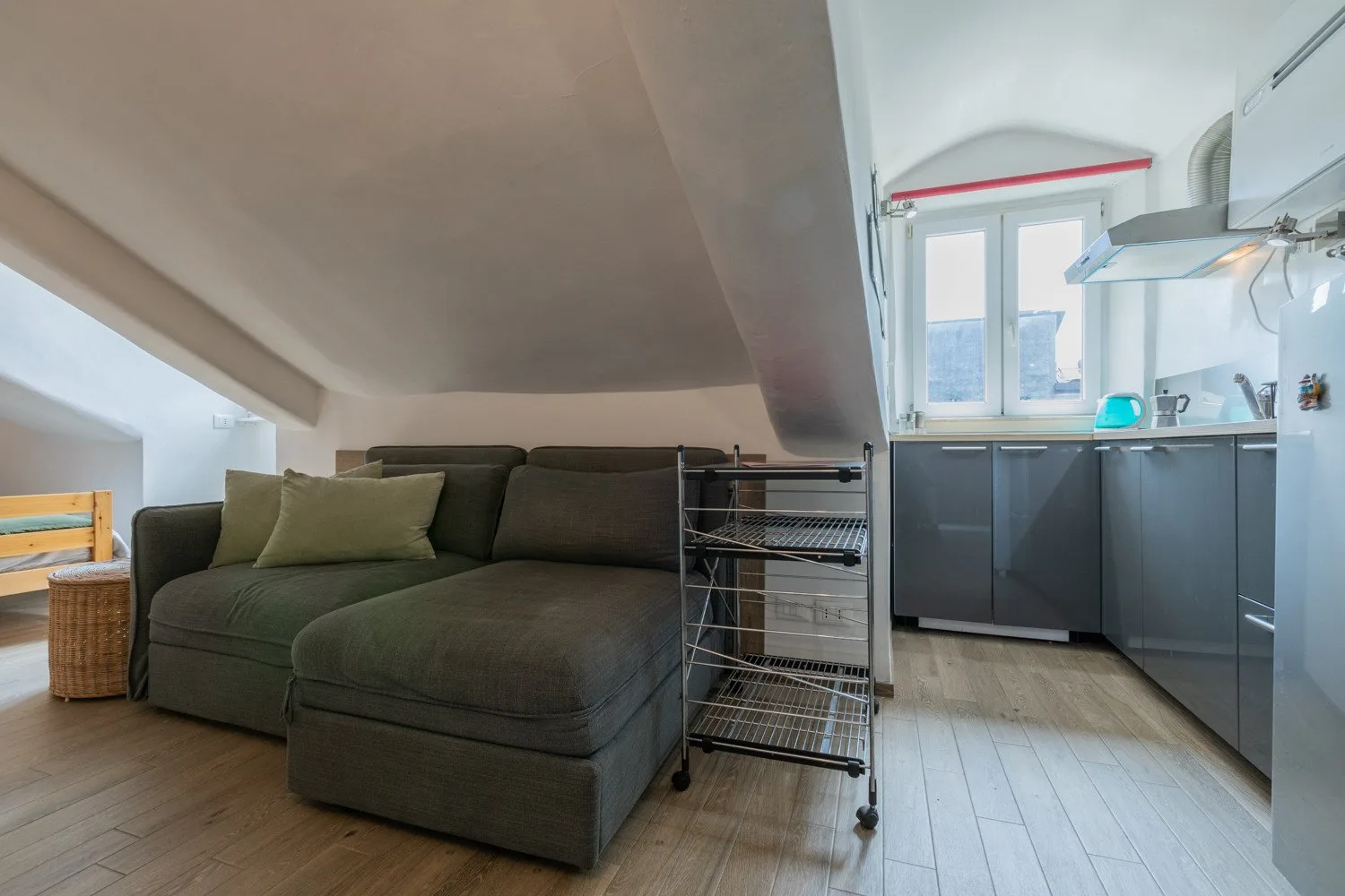 A compact living area with a dark sectional beside a small kitchen.