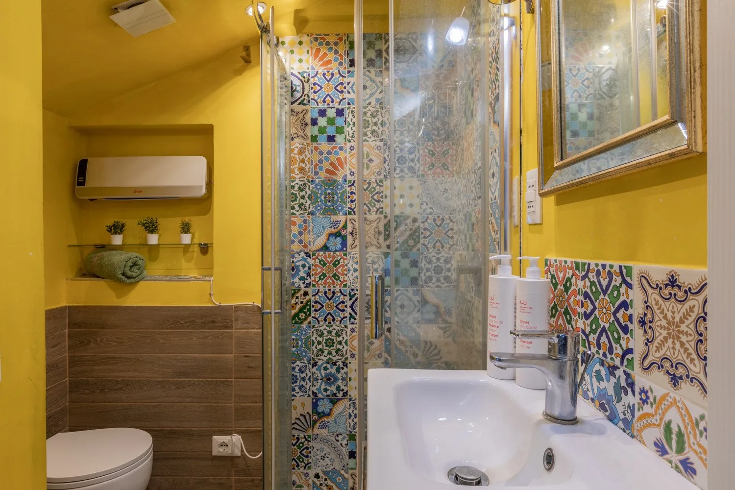 A colorful bathroom with a bathtub, patterned tile, and a glass shower screen.