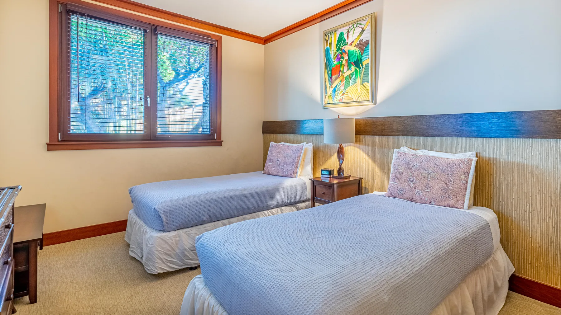 Un dormitorio con dos camas, una ventana y una obra de arte colorida en la pared.