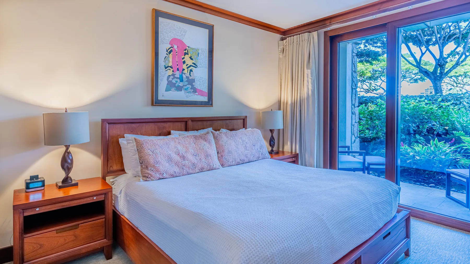 Un dormitorio con una cama grande y puertas corredizas de vidrio hacia la vegetación.