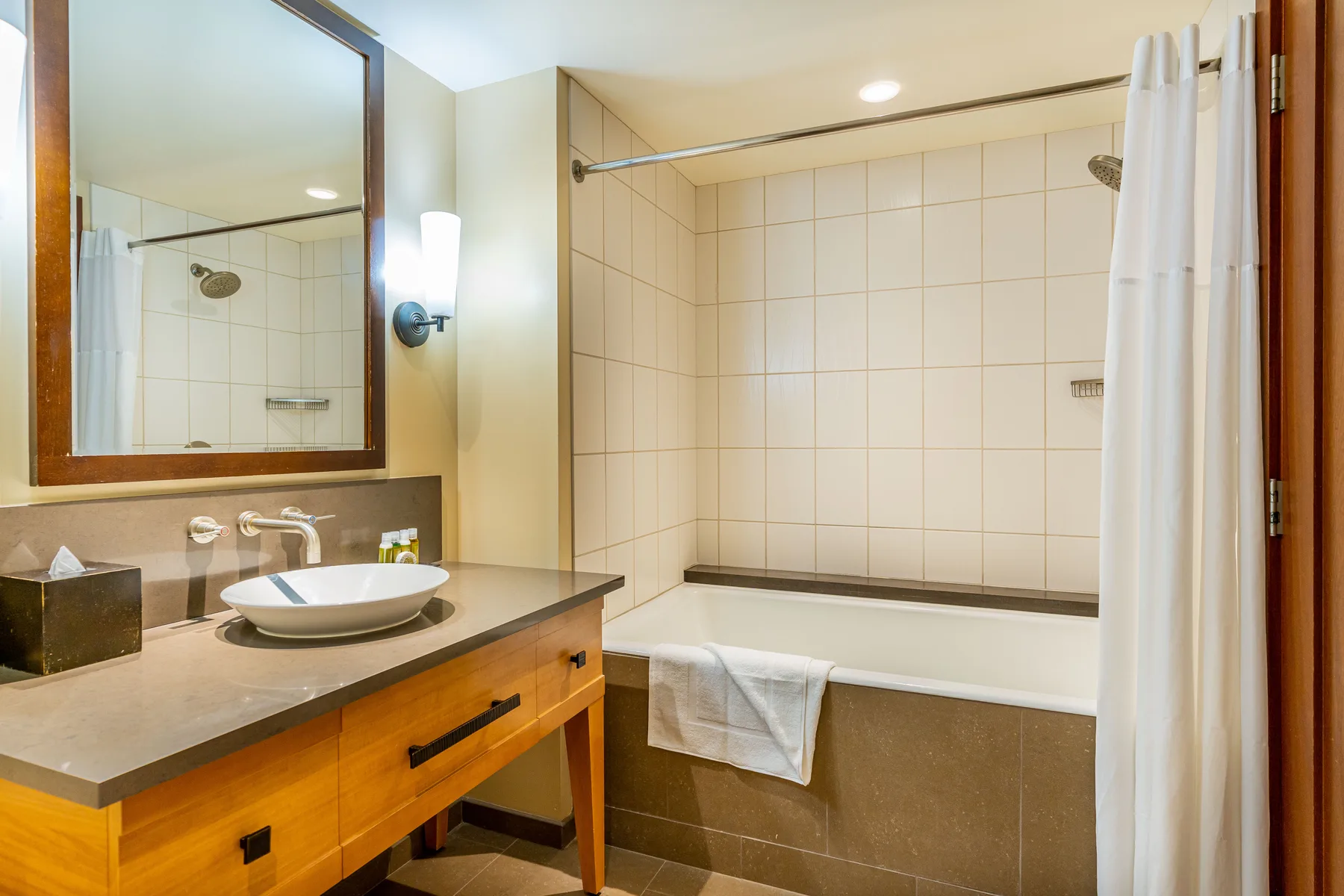 Un baño con lavabo, espejo y bañera detrás de una cortina de ducha.