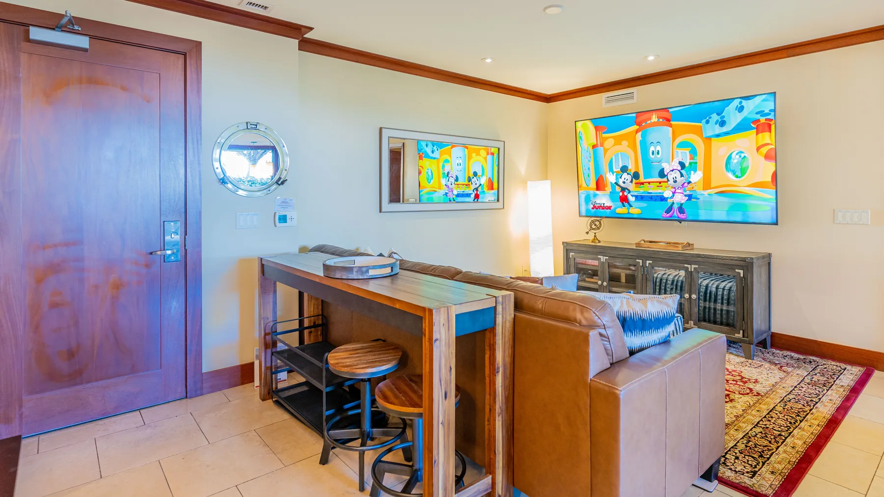 Una sala de estar con sofá, barra de comedor y una pantalla colorida en la pared.