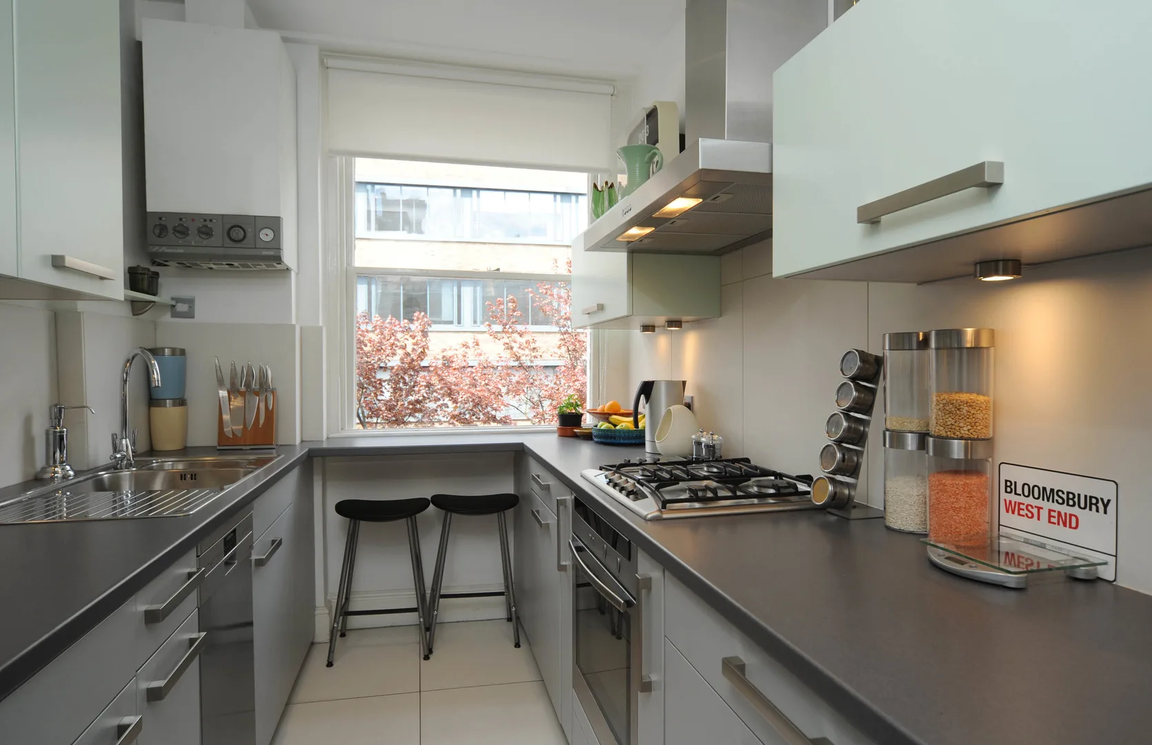 A modern kitchen with dark countertops, a gas cooktop, and a large window.