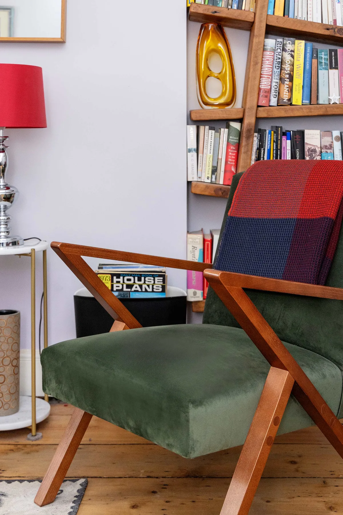 A reading nook with a green upholstered chair beside a bookshelf.