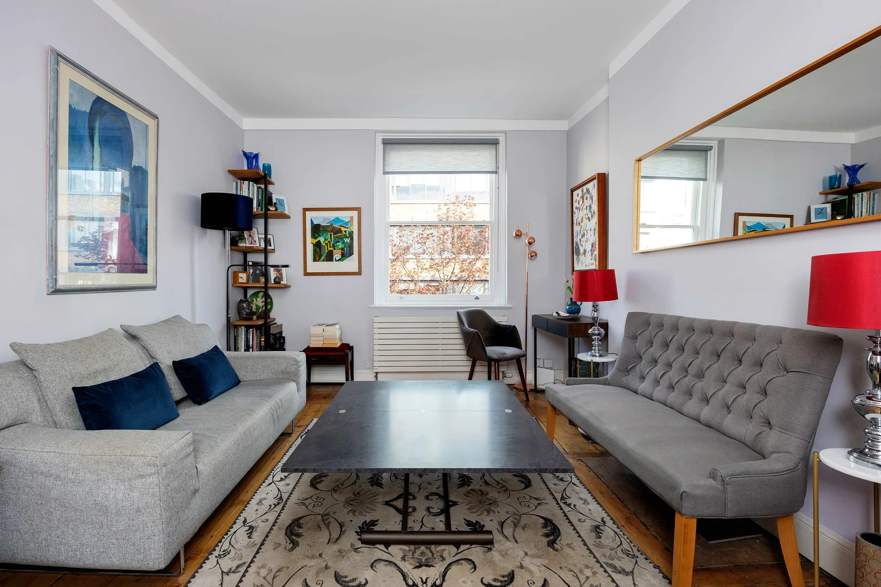 A living room with seating arranged around a coffee table and patterned rug.