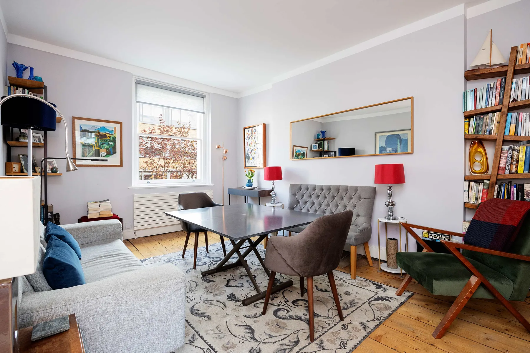 A bright living and dining room with a table, seating, and bookshelves.