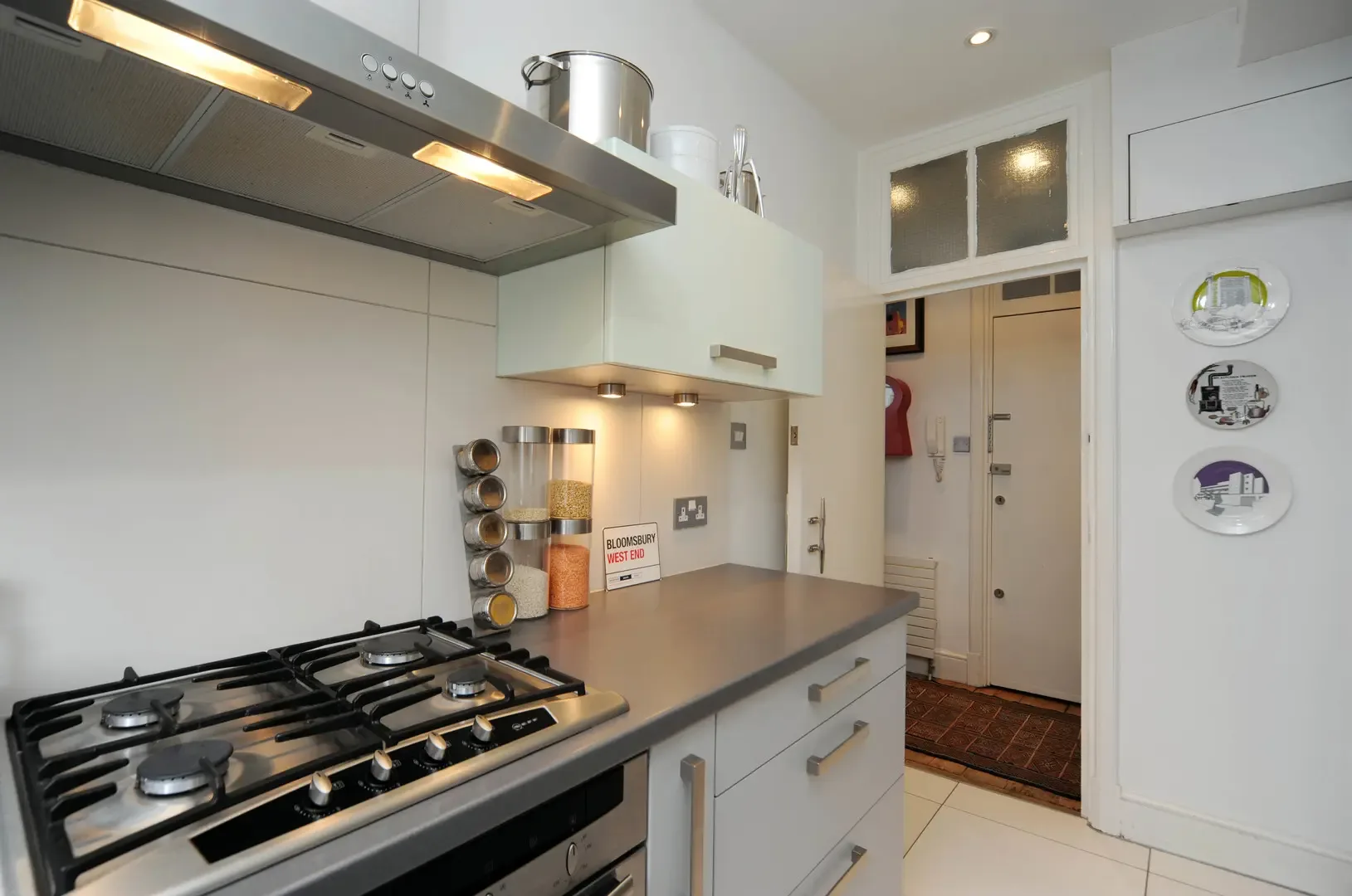 A compact kitchen with a gas cooktop and stainless steel range hood.