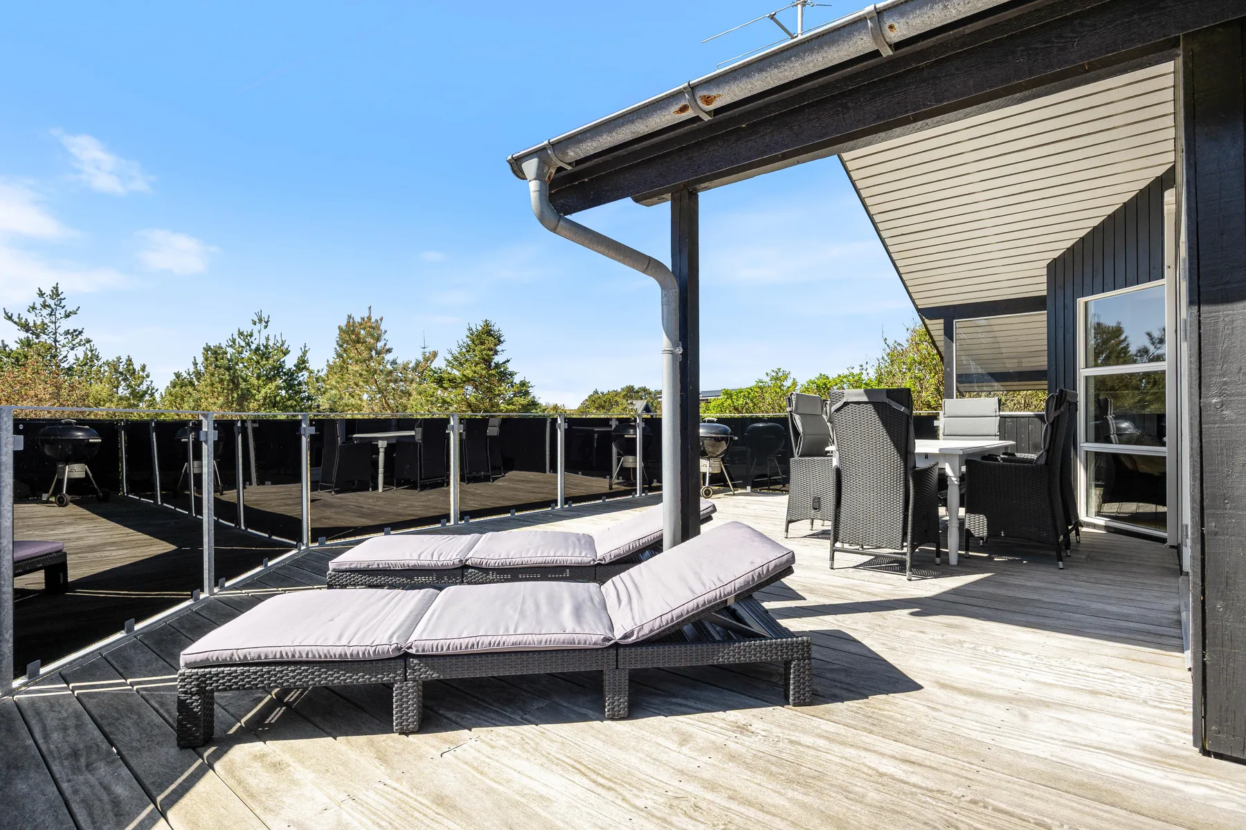 Una terraza exterior con tumbonas acolchadas y una zona de estar cubierta.