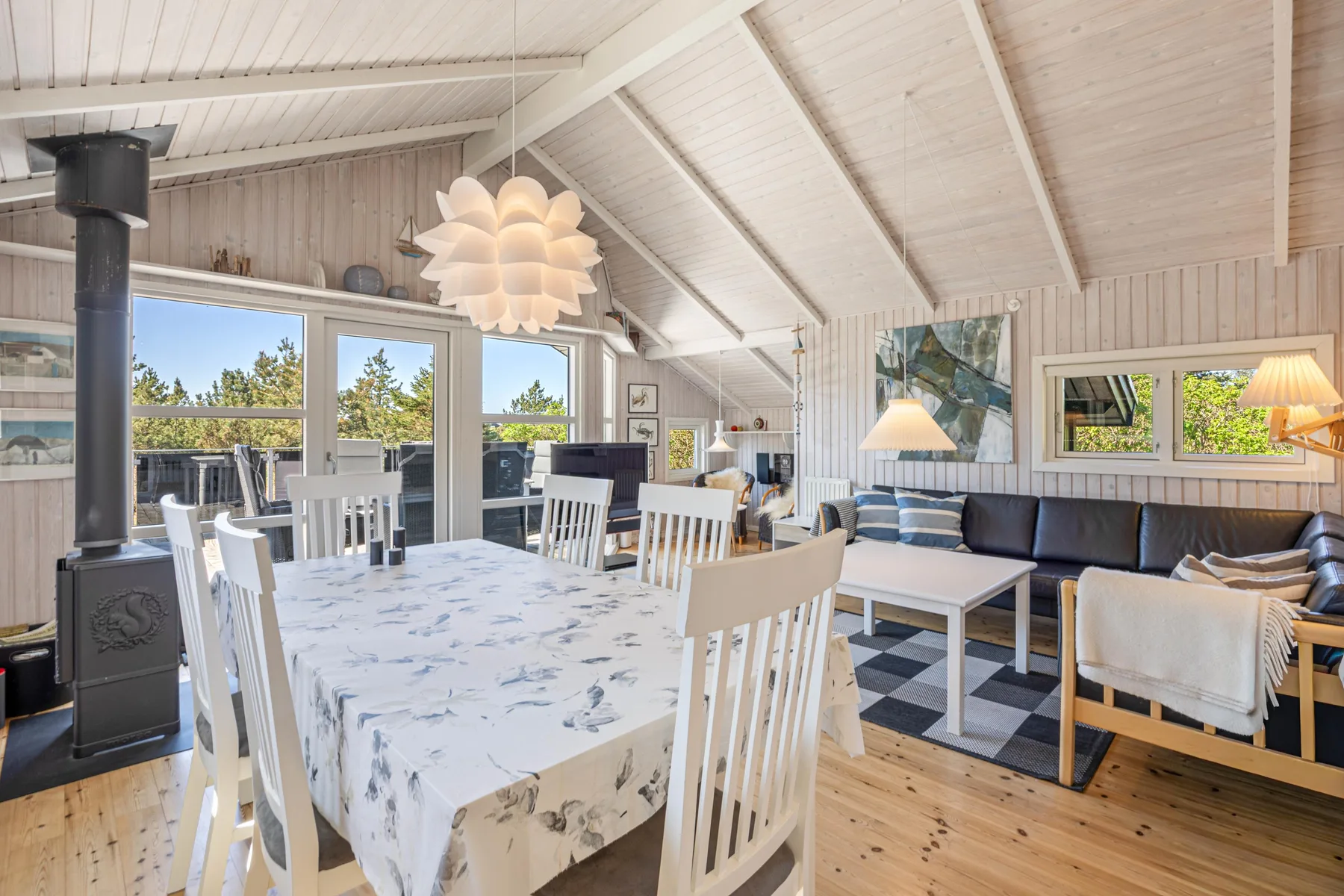 Una luminosa sala de estar y comedor cuenta con una mesa y asientos junto a grandes ventanas.