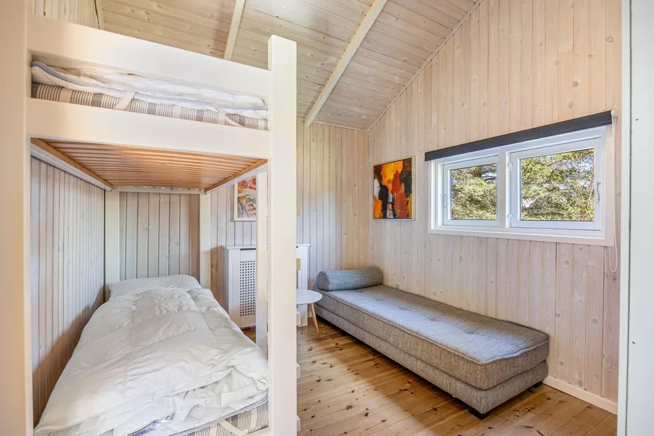 Dormitorio compacto con literas, una cama baja y una ventana.