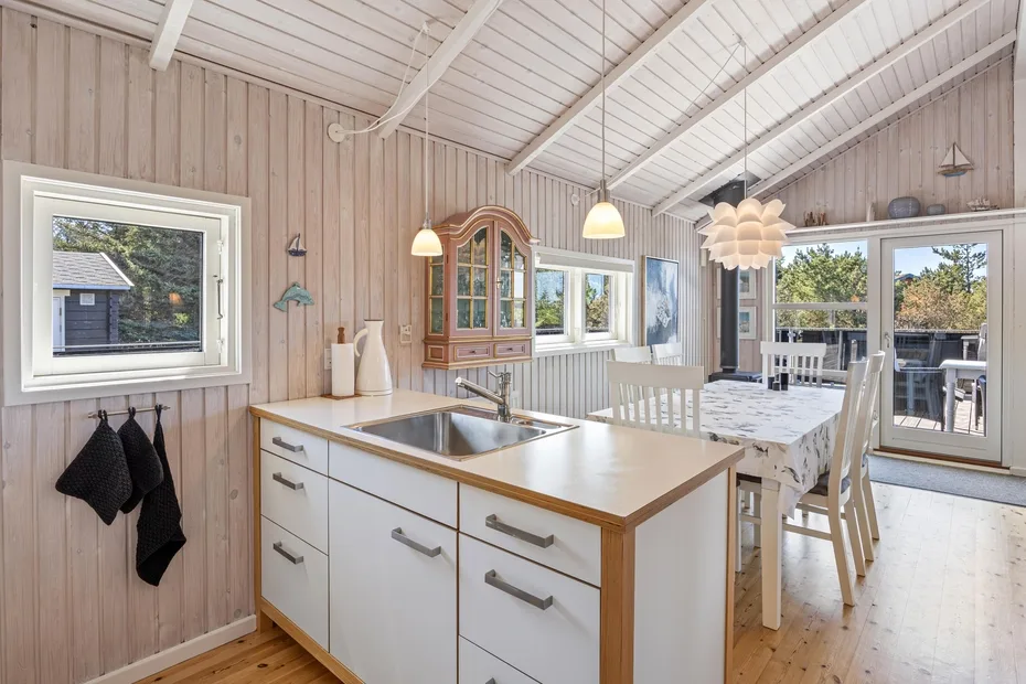Una luminosa cocina y comedor con una isla central y grandes ventanas.