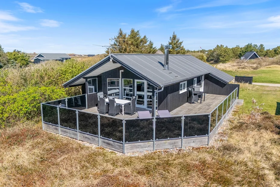 Una casa moderna con una terraza exterior cercada y asientos de patio.