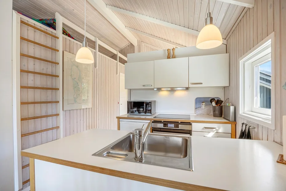 Una cocina luminosa con una isla central, fregadero y armarios blancos.